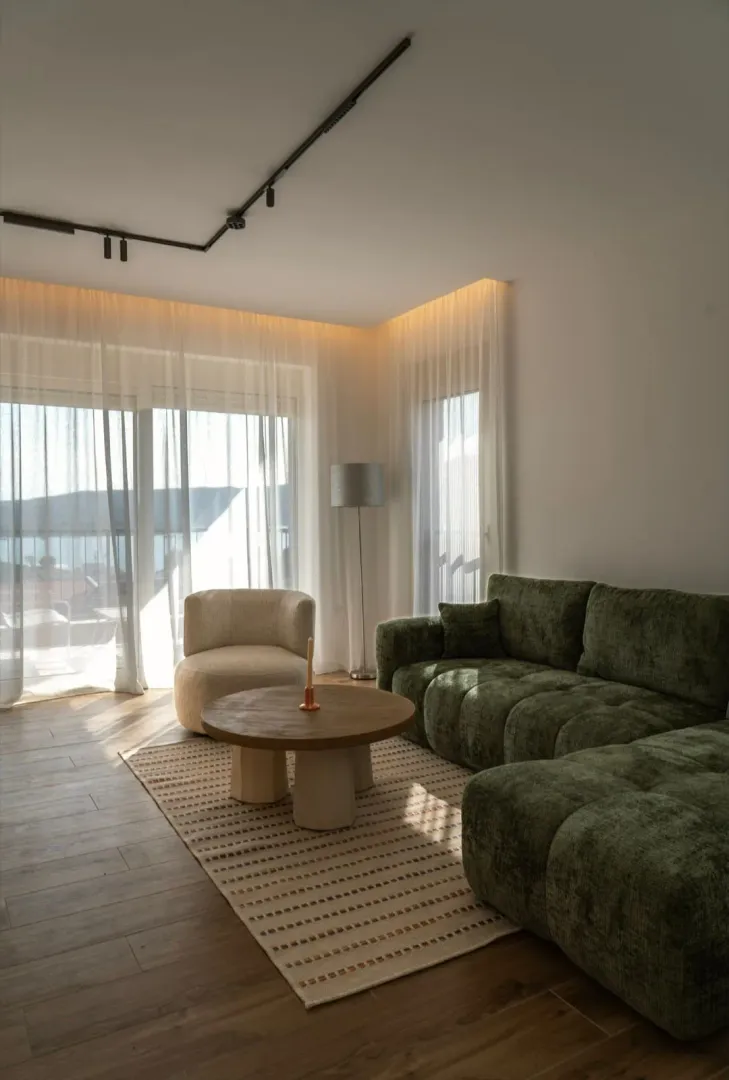 Modern and bright living room with a green sectional sofa and a rug.