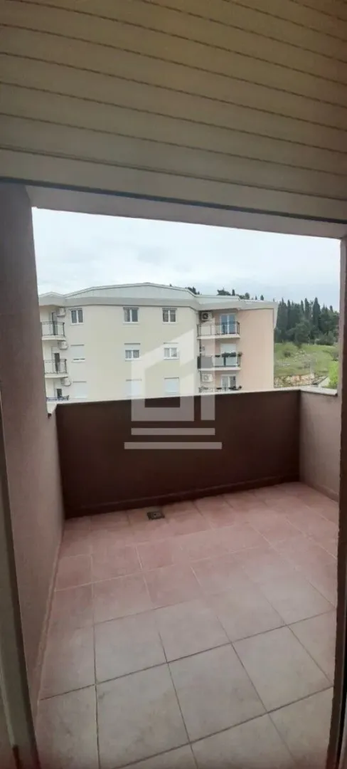 Pogled sa popločane terase na okolne zgrade i zelenilo.