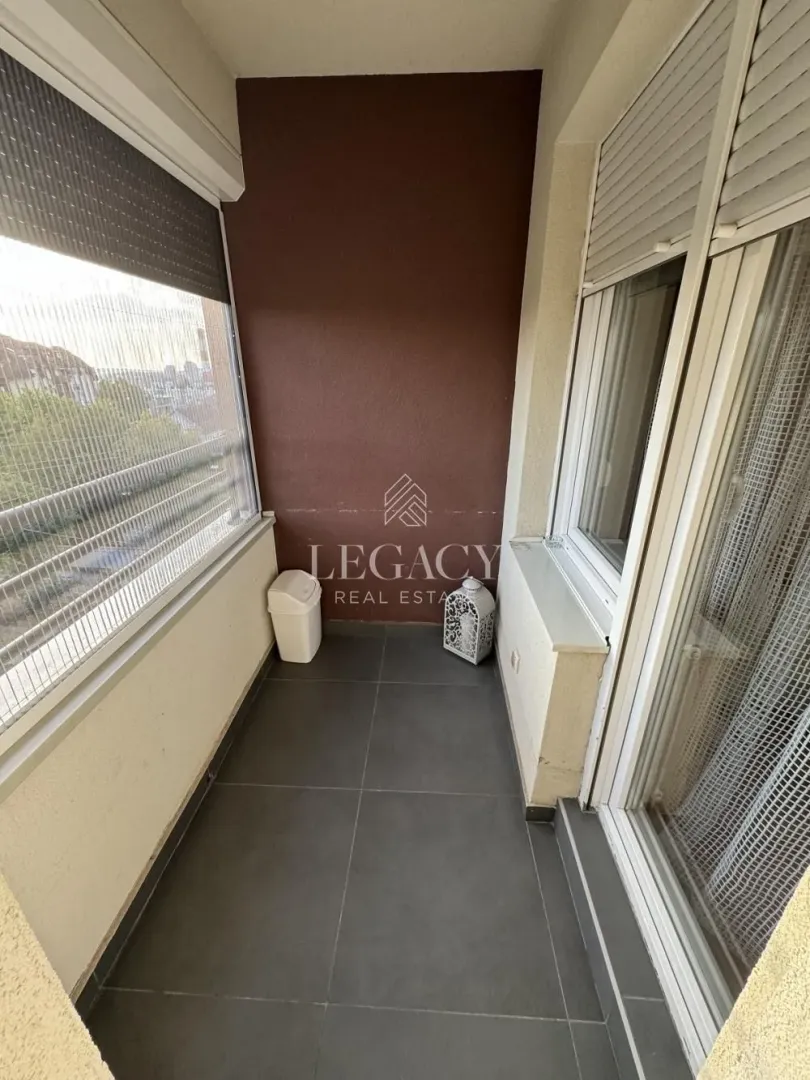 Manji zastakljeni balkon sa keramičkim pločicama na podu.