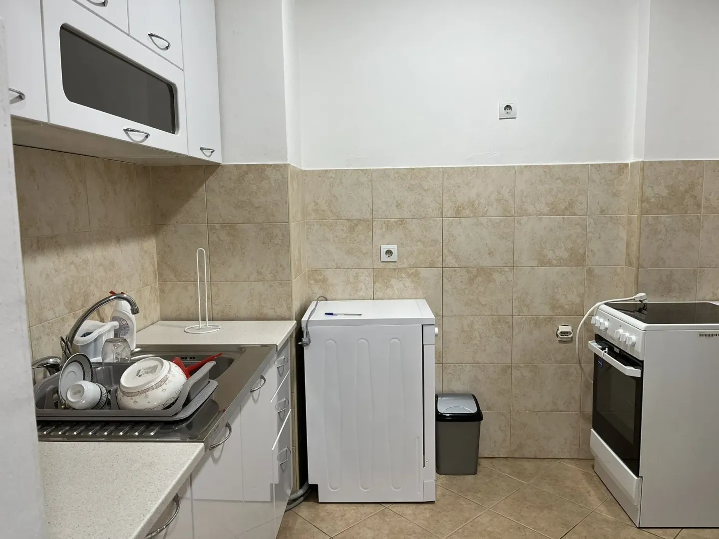 A simple kitchen with white cabinets, a stove, and a sink.