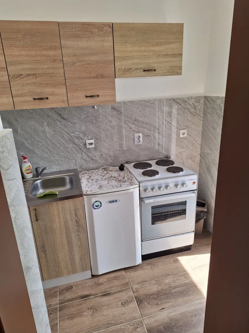 Small kitchen with wooden elements, sink and stove.