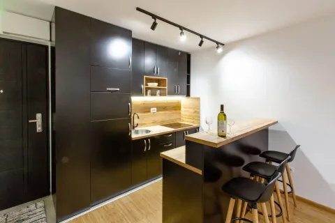 Modern kitchen with dark cabinets and a breakfast bar with stools. - image 7