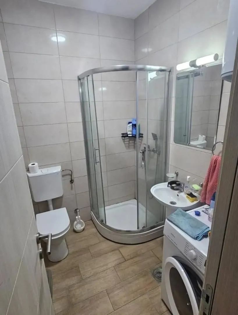 Manje kupatilo sa tuš kabinom, umivaonikom i veš mašinom.