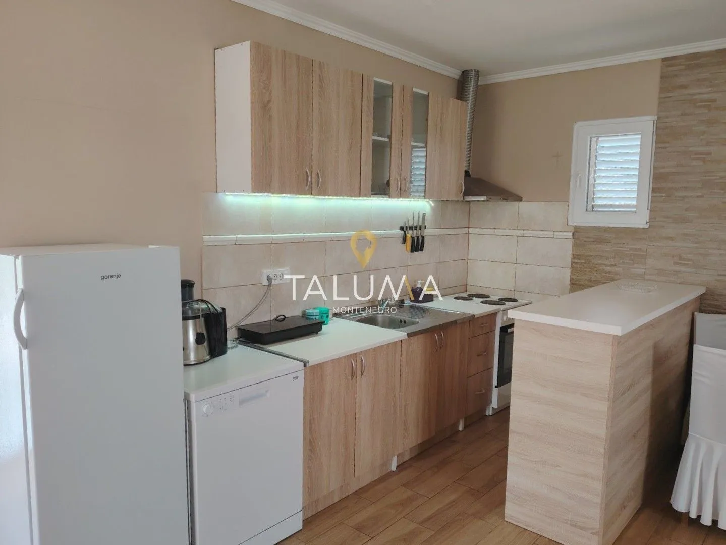 Kitchen equipped with wooden cabinetry, white appliances, and a breakfast bar.