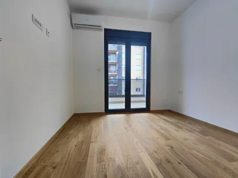 Empty room with wooden flooring, air conditioning, and balcony doors. - image 5