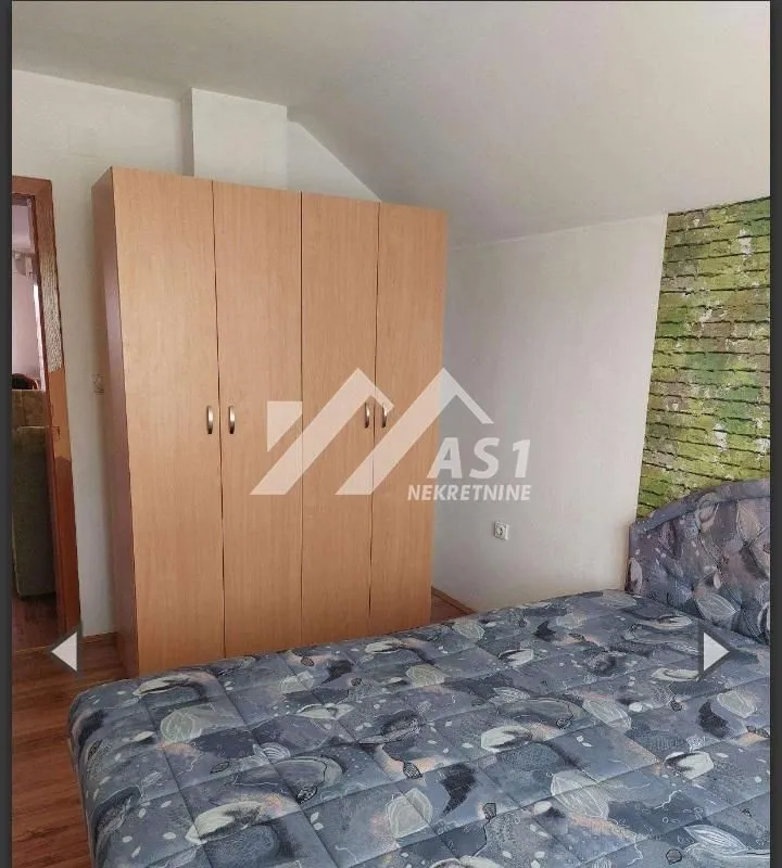 Spavaća soba sa bračnim krevetom i drvenim ormanom.