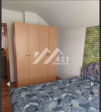 Spavaća soba sa bračnim krevetom i drvenim ormanom. - image 4