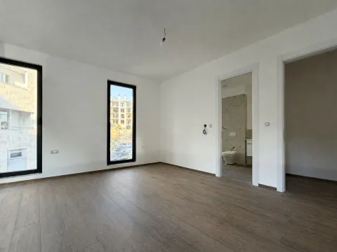 Prazna soba sa bijelim zidovima, drvenim podom i dva prozora. - image 6