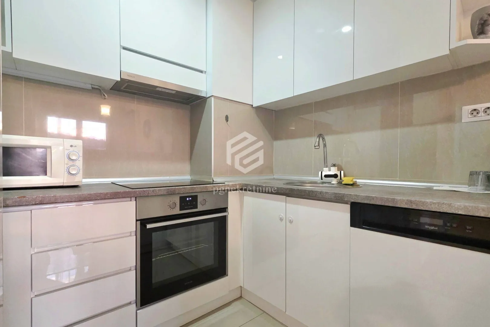 Small modern kitchen with white cabinetry and built-in appliances.