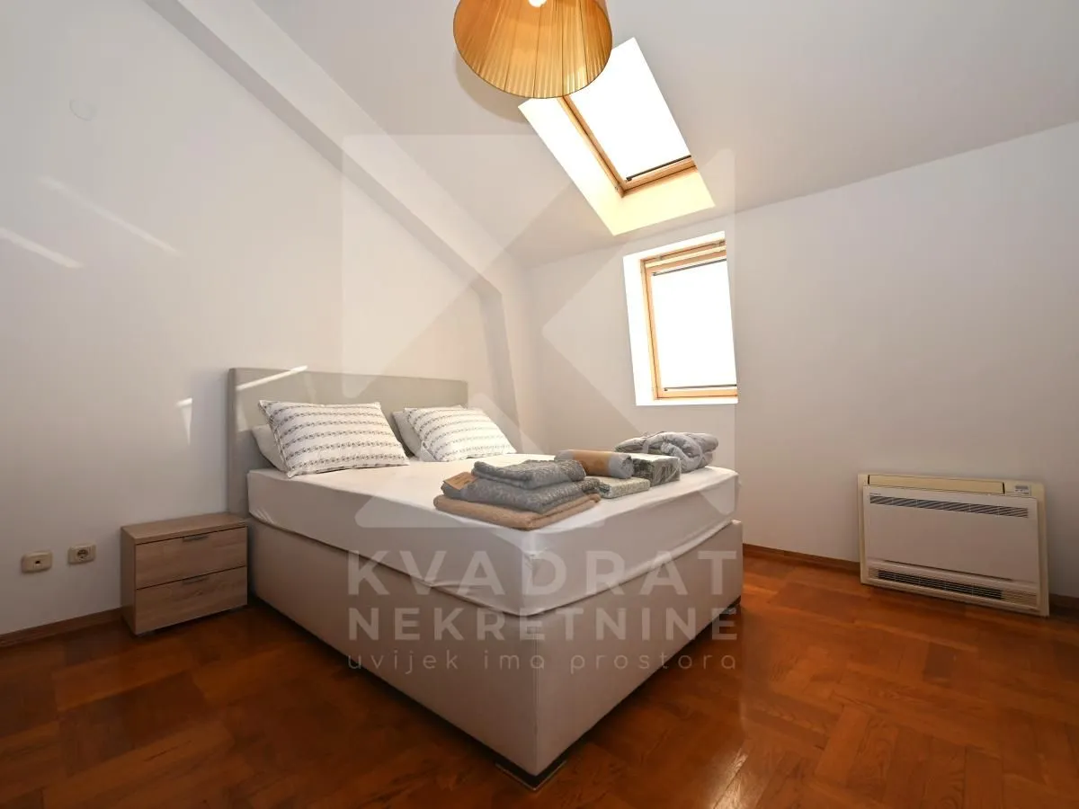 Bedroom with a double bed, skylight and wooden parquet flooring.