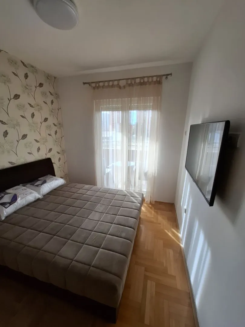 Bright bedroom with a double bed and a wall-mounted TV.