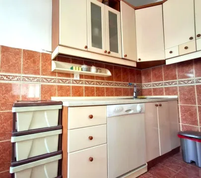 A functional kitchen featuring light cabinets and orange wall tiles. - image 7
