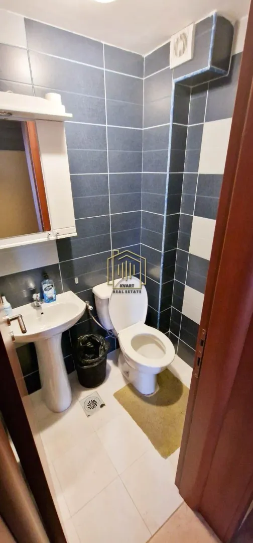 Small tiled bathroom equipped with a toilet and a washbasin.