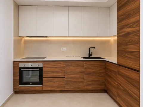 Modern kitchen with wooden cabinetry, built-in oven, and sink. - image 4