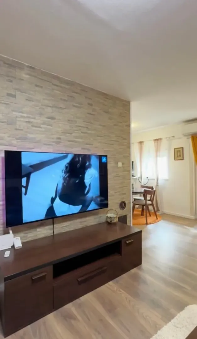 Living room with a wall-mounted TV and a chest of drawers.
