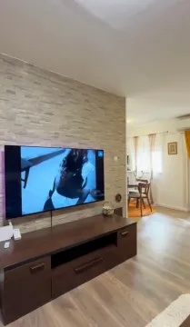 Living room with a wall-mounted TV and a chest of drawers. - image 4