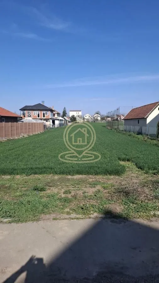 Pogled na ravno građevinsko zemljište sa travnjakom i okolnim kućama.