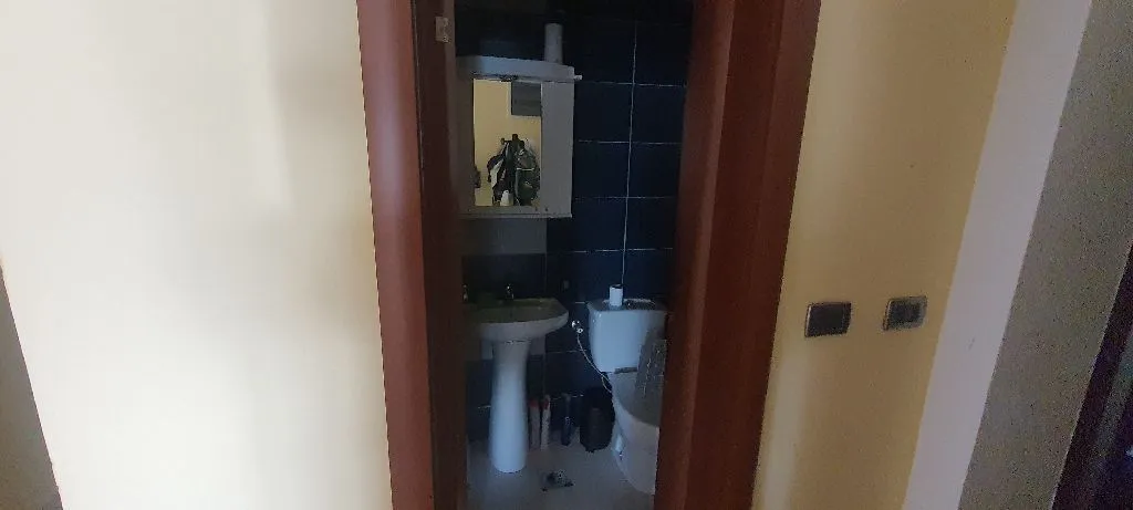 Pogled na manje kupatilo sa umivaonikom i wc šoljom kroz vrata.