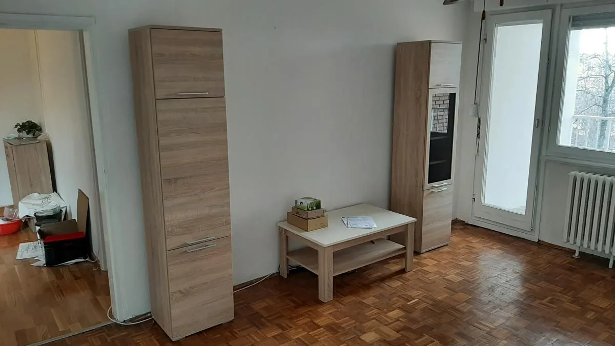 Prazna soba sa drvenim elementima nameštaja i parketom na podu.