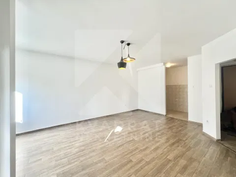 Prazna dnevna soba sa drvenim podom i spojenim manjim dijelom u uglu. - image 3