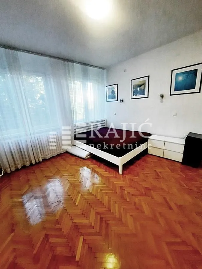 Bedroom with a double bed, parquet flooring, and a large window.