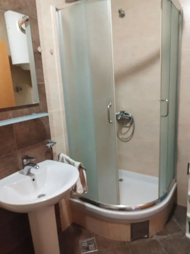 Manje kupatilo sa umivaonikom i tuš kabinom.