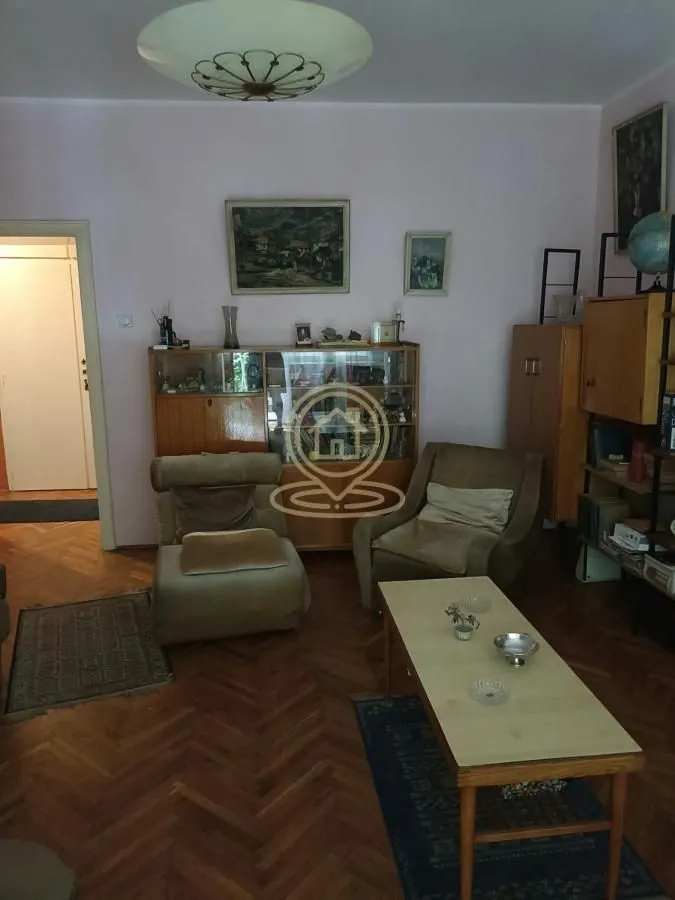 Dnevna soba sa garniturom, klub stočićem i drvenim nameštajem.