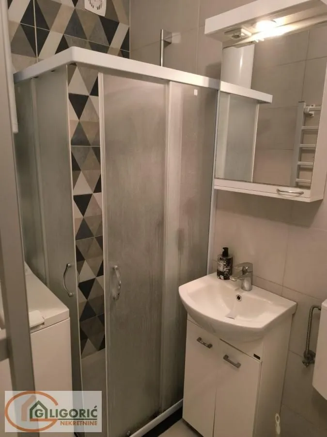 Small bathroom with a shower cabin, washbasin, and a mirrored cabinet.
