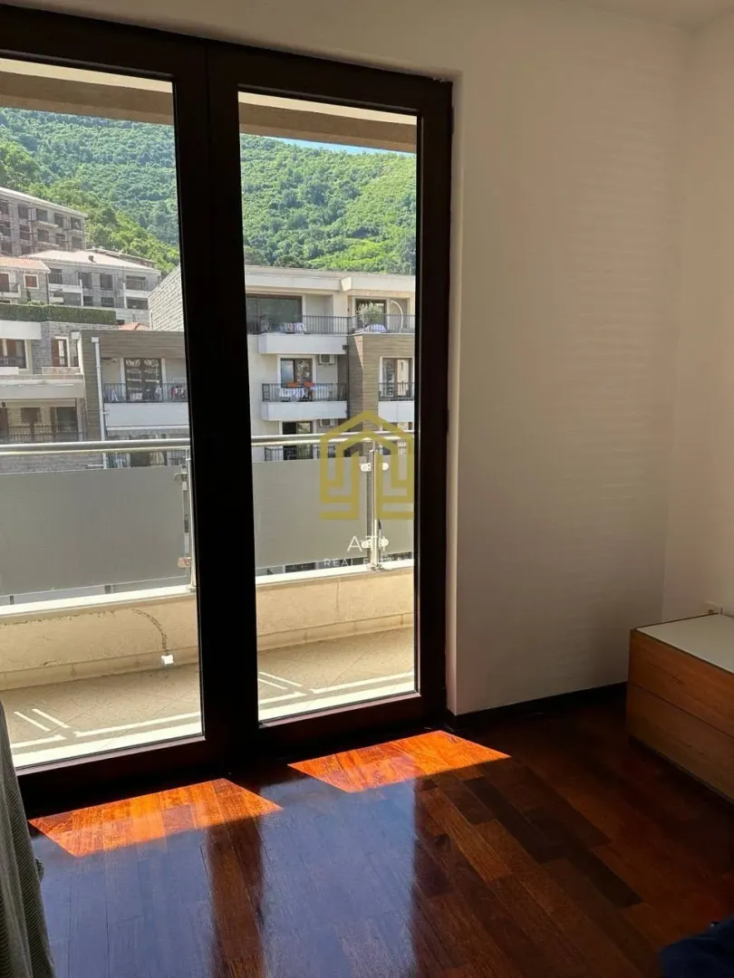 Dnevna soba sa drvenim podom i izlazom na terasu sa pogledom na brda.