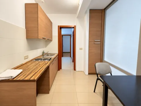 Kitchen with wooden cabinetry, a dining table, and a view through a large window. - image 18