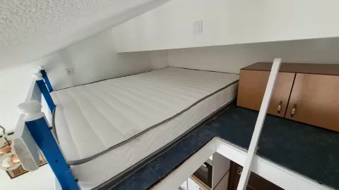 Attic bed with a small cabinet and a ladder. - image 12