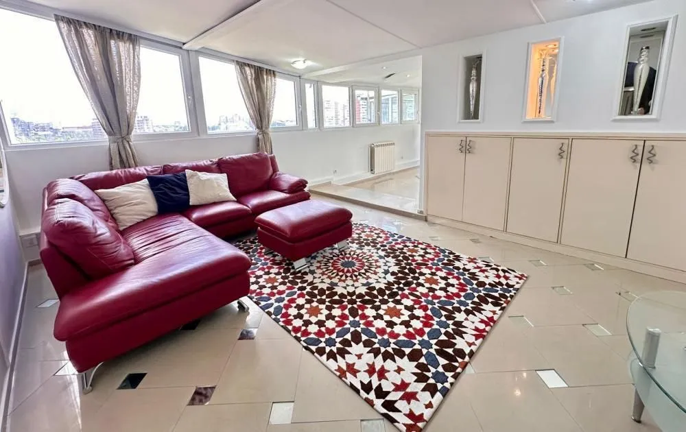Living room with a red sectional sofa, colorful rug, and large windows.