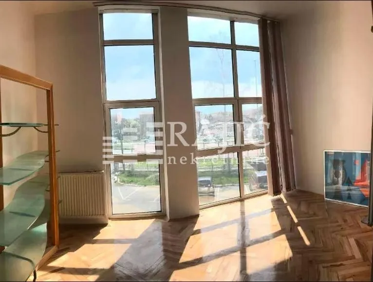 Bright room with large windows and parquet flooring.