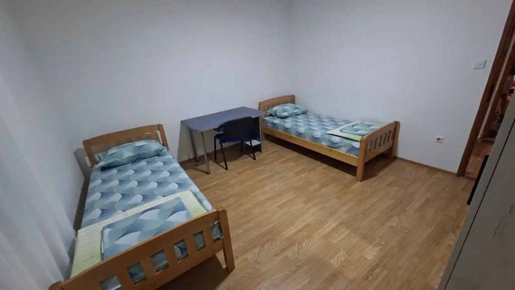 Bedroom with two wooden beds and a desk.