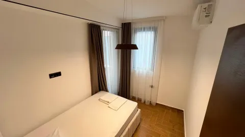 Smaller bedroom with a double bed, curtained window, and laminate flooring. - image 6