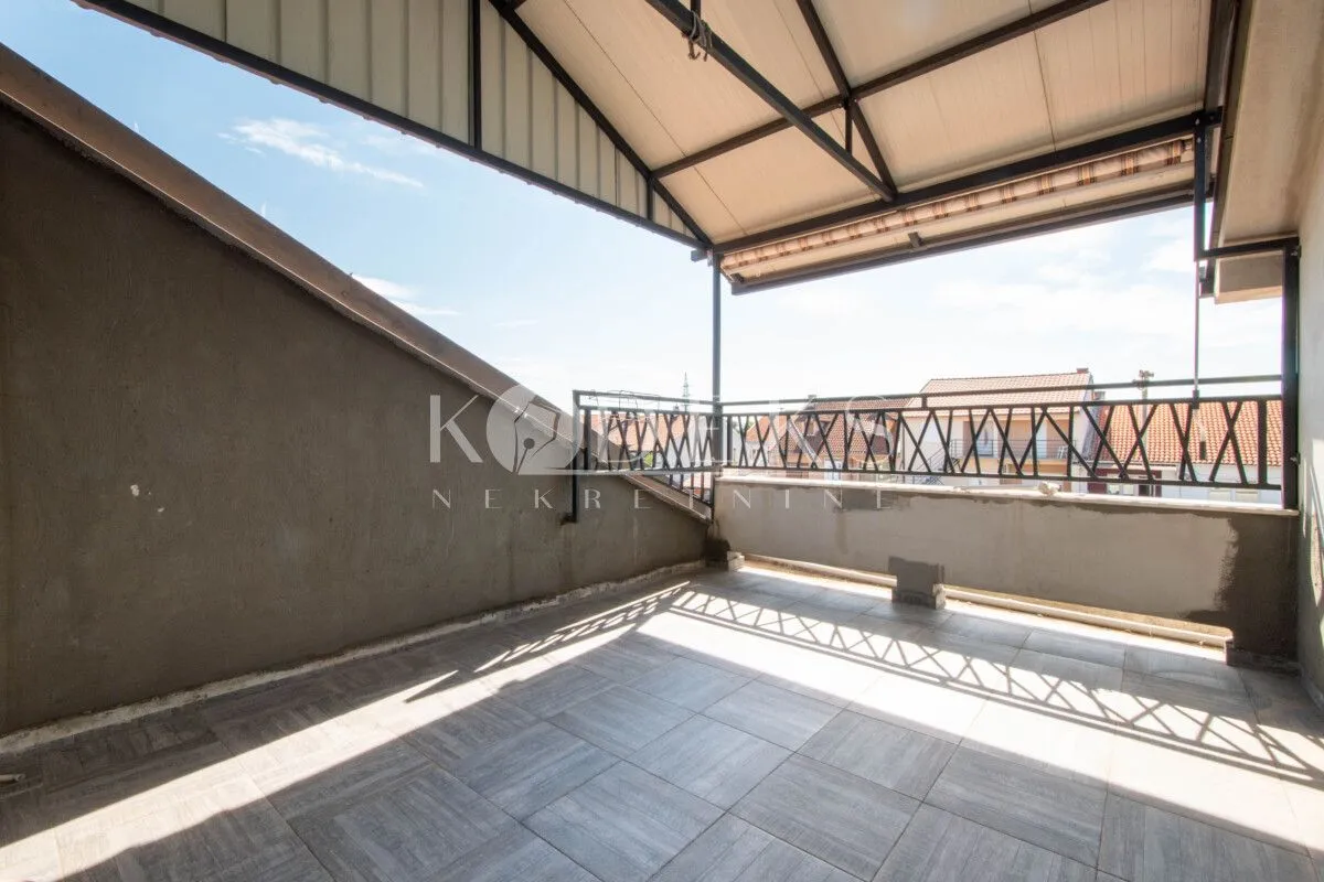 Natkrivena terasa sa keramičkim pločicama i pogledom na okolne kuće.
