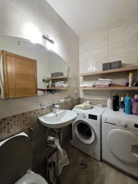 Bathroom with a sink, toilet, and washing and drying machines. - image 12