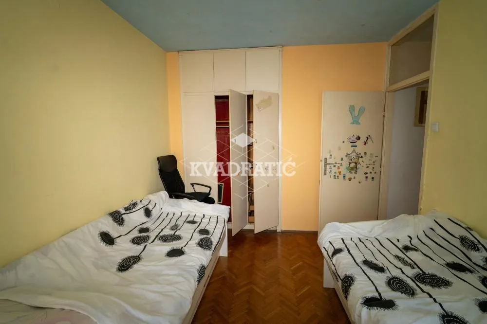 Spavaća soba sa dva kreveta i ugradnim ormanom.