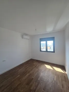 Prazna soba sa bijelim zidovima, drvenim podom i klima uređajem. - image 5