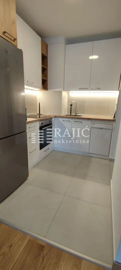 Compact modern kitchen with white cabinetry and built-in appliances.
