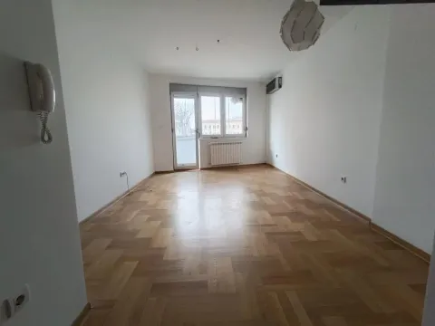Prazna soba sa parketom i balkonskim vratima. - image 2
