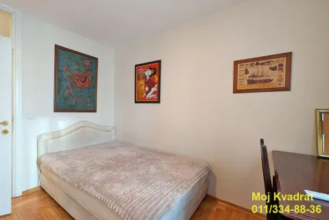 Manja spavaća soba sa krevetom, radnim stolom i slikama na zidu. - image 7