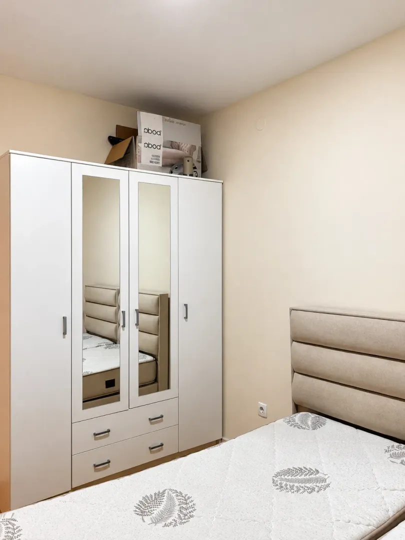 Bedroom with a bed and a white wardrobe with mirrors.
