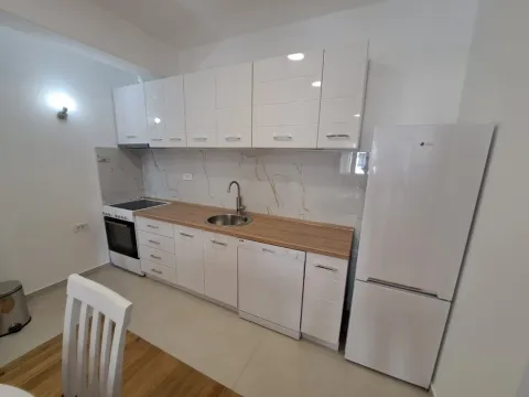 Modern white kitchen with white cabinetry, a wooden countertop, and a refrigerator. - image 7