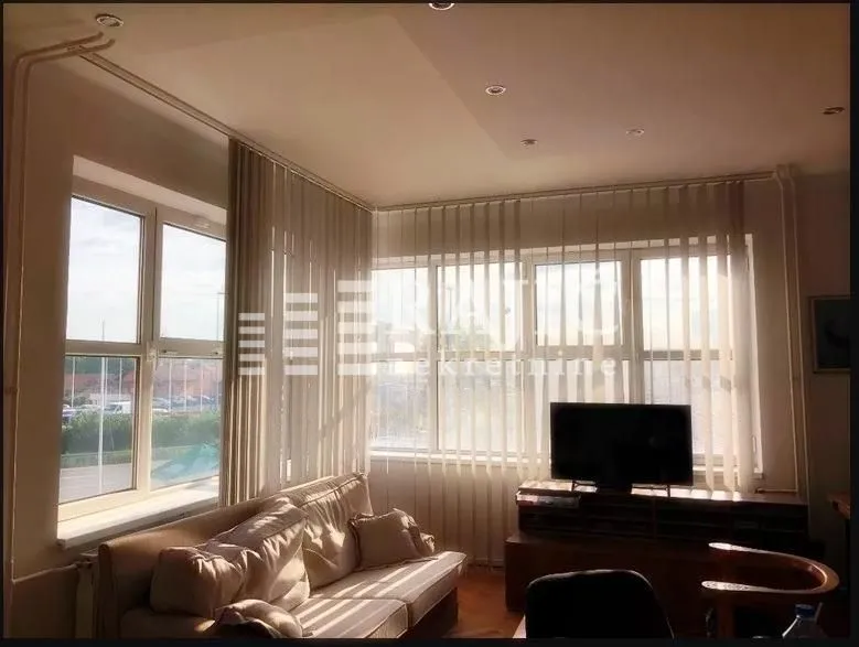 Living room with seating furniture, television, and large windows.