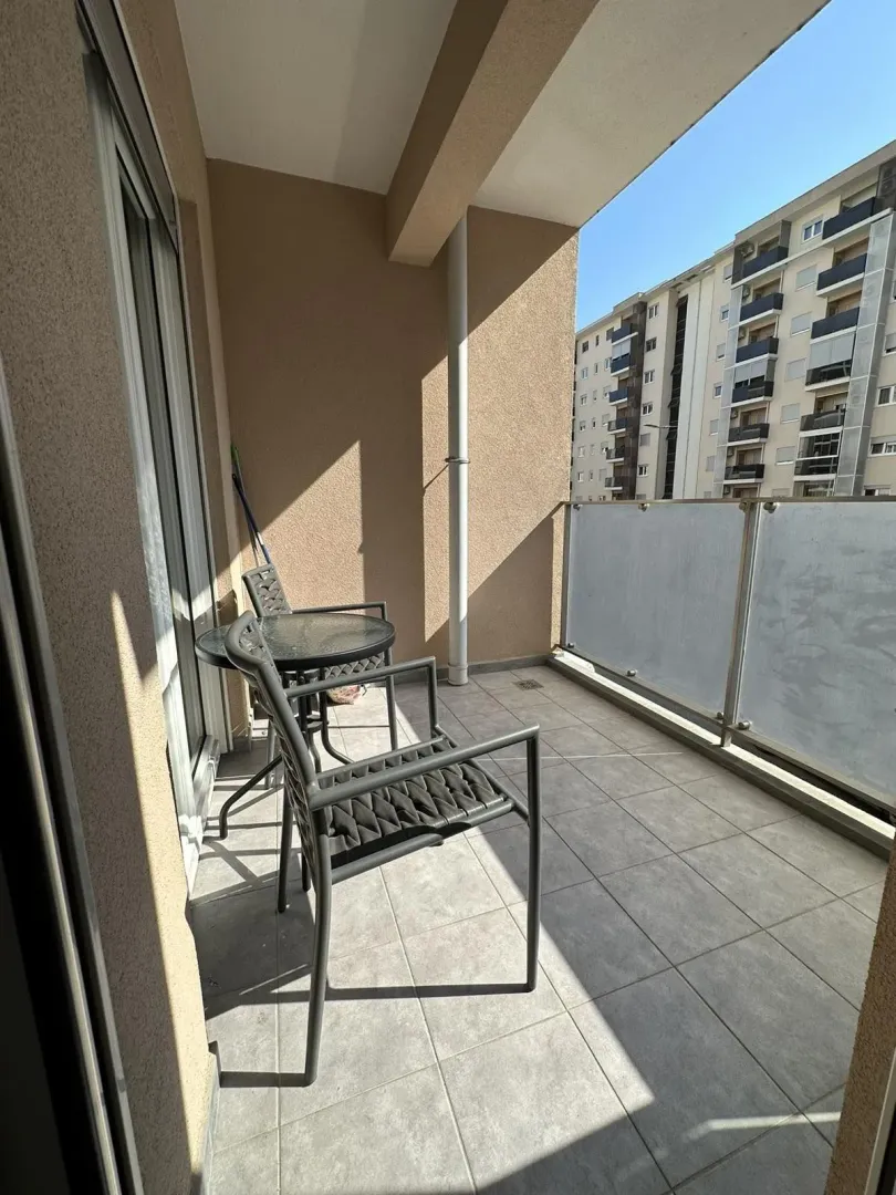 A balcony with outdoor seating and a view of neighboring buildings.