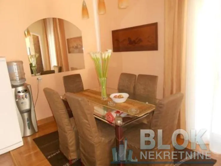 Dining area with a table, chairs, and a wall mirror.