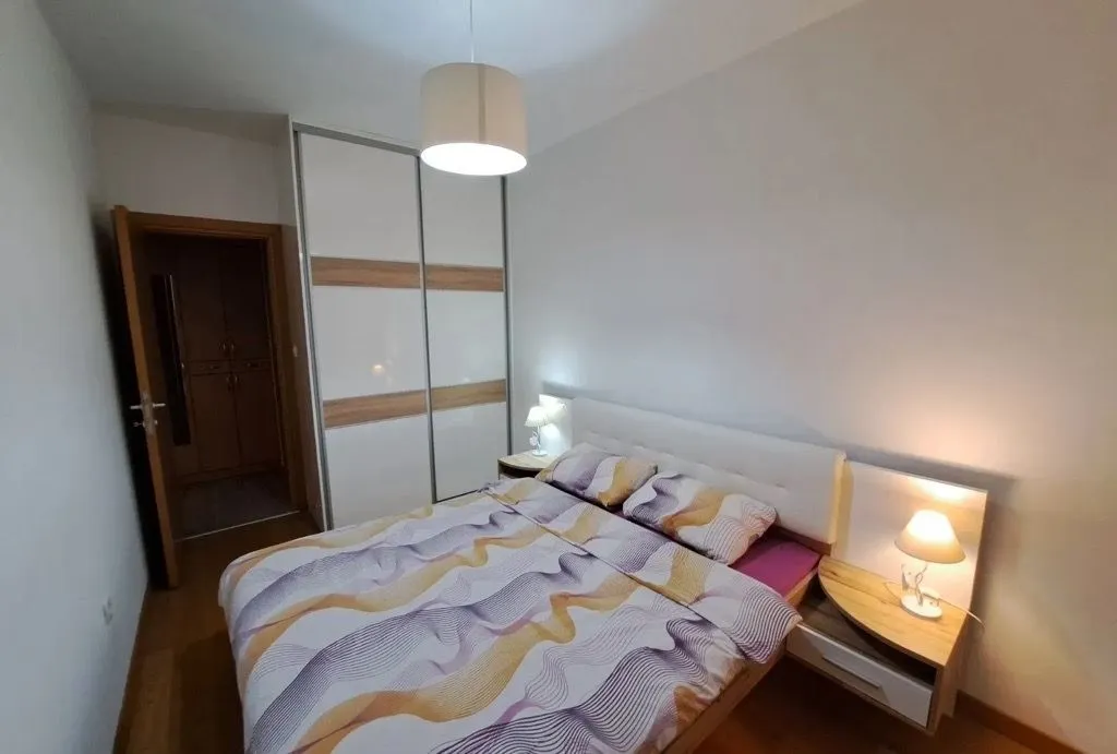 Furnished bedroom with a double bed, wardrobe, and bedside lamps.