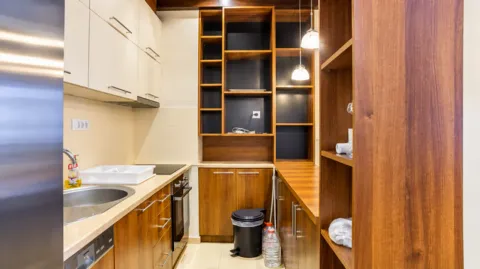 Kuhinja opremljena drvenim elementima i ugrađenim kućnim aparatima. - image 14