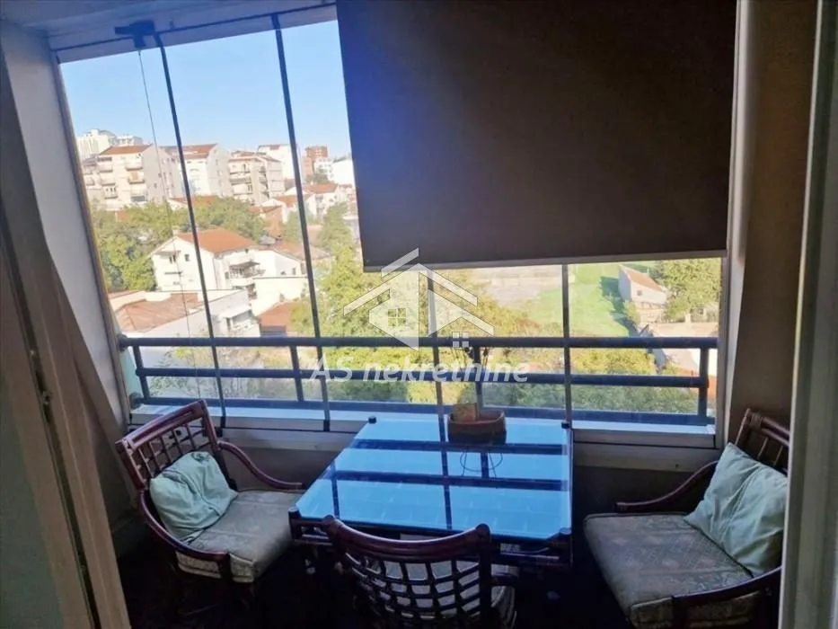 Enclosed balcony with a dining table and a city view.